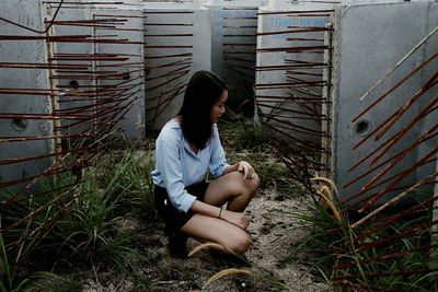 Full length of young woman crouching at construction site