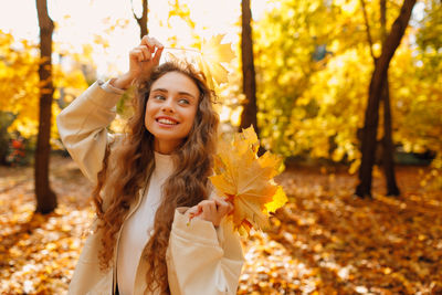 Portrait of young woman standing by tree