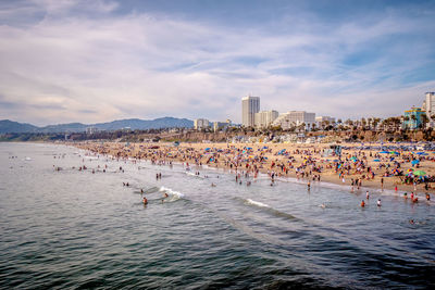 Group of people on beach in city against sky