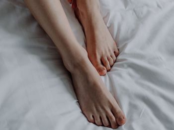 Low section of woman lying on bed