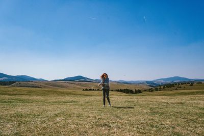 Full length of woman standing on field against sky