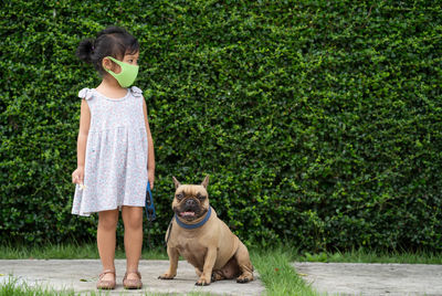 Little girl with protective face mask to prevent virus and pm2.5 walk the dog at field.