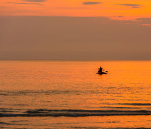 Silhouette boat in sea against orange sky