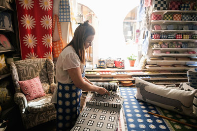 Serious woman cutting fabric swatch while working in shop