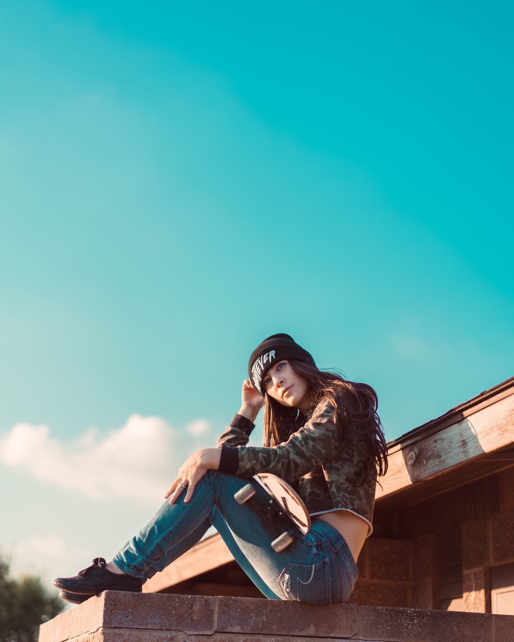 one person, leisure activity, real people, front view, outdoors, lifestyles, full length, casual clothing, day, young adult, young women, beautiful woman, low angle view, sitting, built structure, sky, nature, smiling, happiness, architecture, beauty in nature