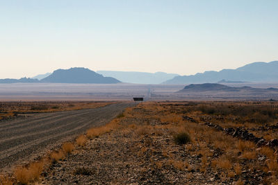 Scenic view of land and mountains against clear sky