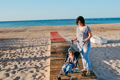 Mother with son in baby stroller at beach