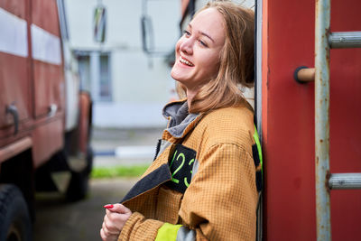 Portrait of young woman standing in car