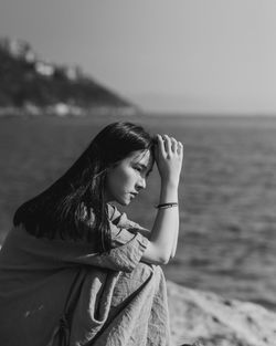 Young woman looking at sea shore against sky