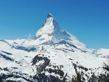 Scenic view of snowcapped mountains against clear blue sky