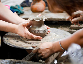 Cropped hands of people working with earthenware