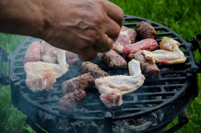 Cropped hand preparing food on barbecue grill