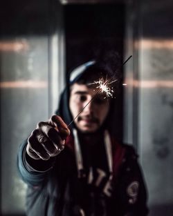 Man with burning sparkler against wall