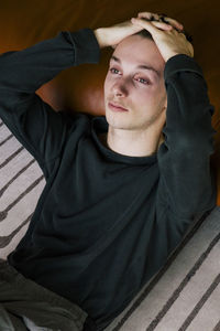 High angle view of depressed man reclining on sofa at home