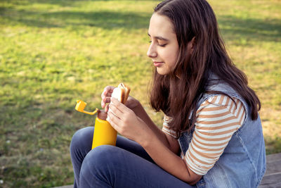Young woman drinking milk in park