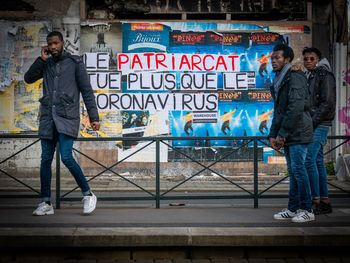 Full length portrait of man standing against graffiti in city