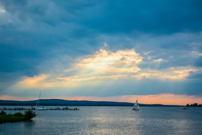 Sailboat sailing in sea against sky during sunset