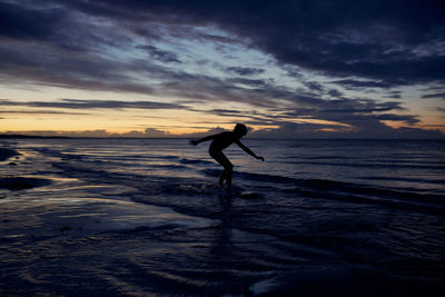 Silhouette man on beach against sky during sunset