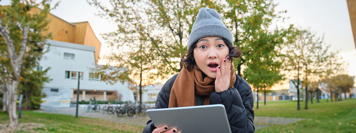 Portrait of young woman using laptop while sitting in park