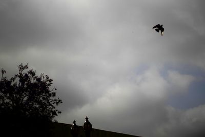 Low angle view of people against cloudy sky