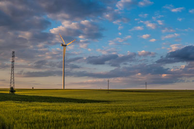 Windmills on field against sky