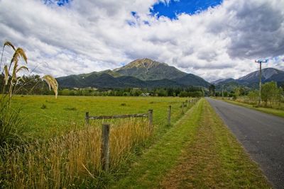 Road amidst field against sky