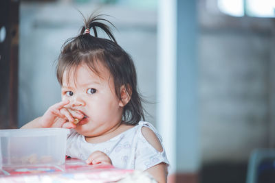 Portrait of cute baby girl eating food at home