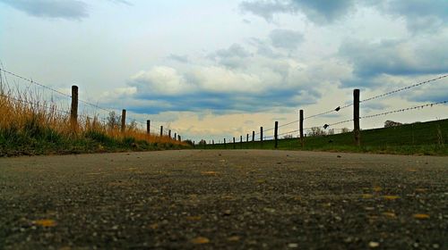 Surface level of road against cloudy sky