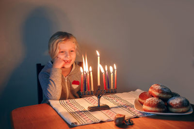 Girl lighting candles on menorah for traditional jewish hanukkah holiday. child celebrating chanukah