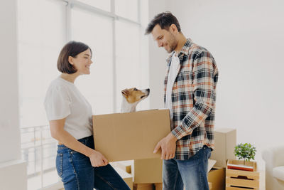 Man and woman holding box with dog at home