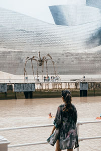 Rear view of man standing on bridge over river