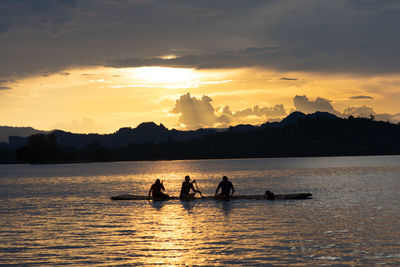 Silhouette people on boat against sky during sunset
