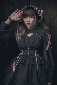 Portrait of young woman standing against wall