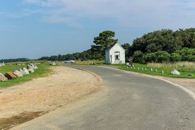 Road amidst trees and buildings against sky