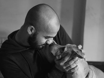 Side view of a bald man playing with a dog