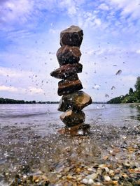 Stack of stones at beach against sky
