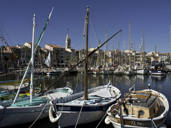 Boats moored at harbor against clear sky