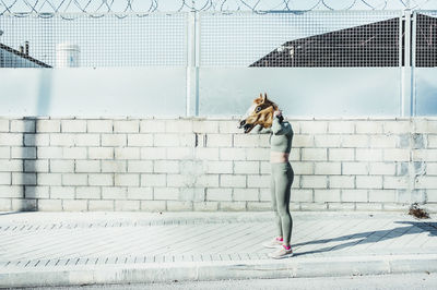 Woman with umbrella on footpath against wall