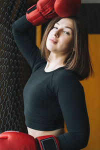 Young brunette woman in black wear engaged boxing training in the fitness club gym