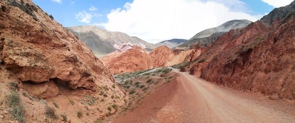 Panoramic view of red gravel road amidst andes mountains against sky
