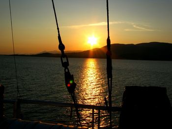 Silhouette man holding sea against sky during sunset