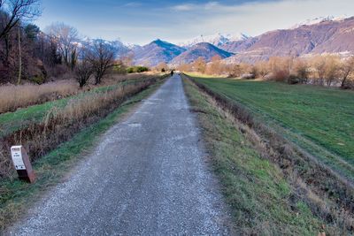 Empty road amidst field against sky