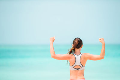 Rear view of woman standing in sea against sky