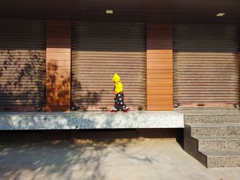 Side view of boy walking by closed shutter 