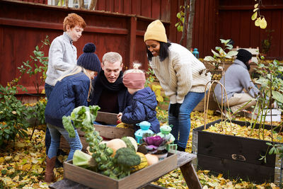 Male and female talking to children while man collecting fresh produce in yard