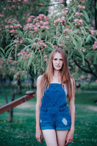 Portrait of beautiful young woman standing against plants