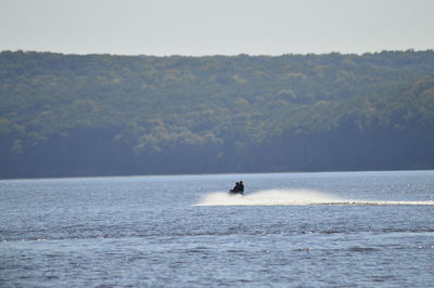 Person riding boat in sea against sky