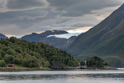 Scenic view of river by mountains against sky