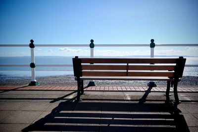 Empty bench at park against clear sky