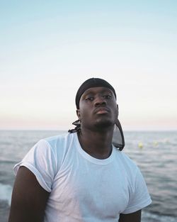 Portrait of man with headscarf standing at beach against sky